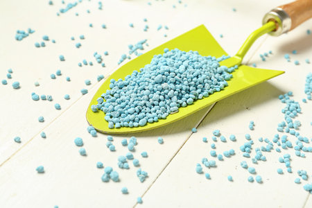 Gardening shovel with blue granular fertilizer on white wooden background, closeupの写真素材