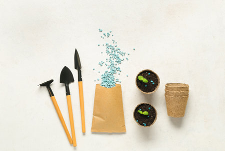 Gardening tools, peat pots and bag with blue granular fertilizer on white backgroundの写真素材