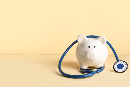 Piggy bank with stethoscope on beige backgroundの写真素材