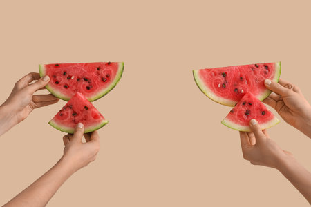 Female hands with slices of ripe watermelon on beige backgroundの写真素材