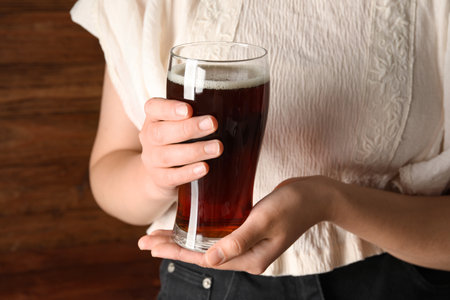 Woman with glass of tasty kvass on wooden backgroundの写真素材