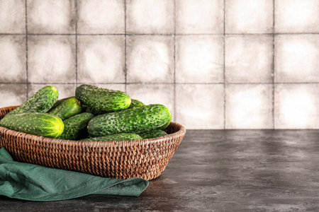Wicker bowl with fresh cucumbers on tableの写真素材