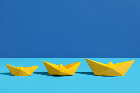 Yellow origami boats on color backgroundの写真素材