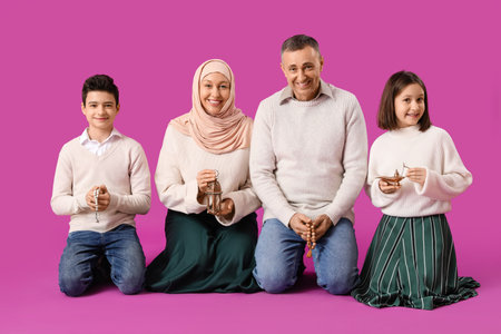 Happy Muslim family with traditional accessories on pink background. Eid al-Fitr celebrationの写真素材