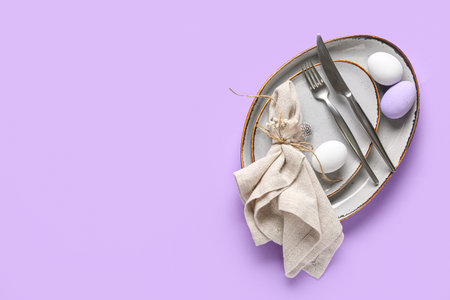 Beautiful table setting with Easter eggs and gypsophila flowers on lilac backgroundの写真素材