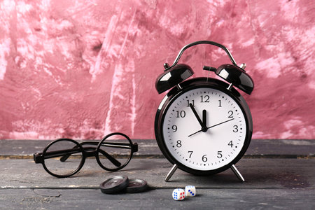 Composition with alarm clock and glasses on wooden table against pink background. Time management conceptの写真素材