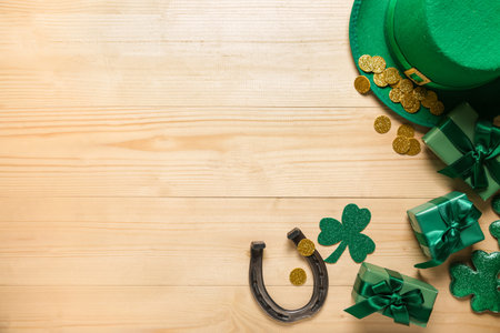 Gift boxes with leprechaun hat, horseshoe and decor for St. Patrick's Day celebration on light wooden backgroundの写真素材