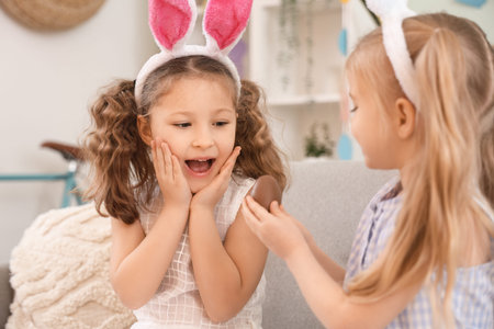 Surprised little girl receiving chocolate Easter egg from her friend at home, closeup