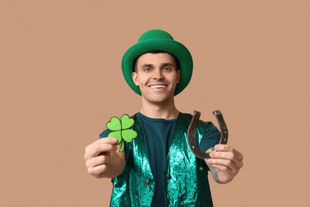 Happy young man in green clothes, with shamrock and horseshoe on beige background. St. Patrick's Dayの写真素材