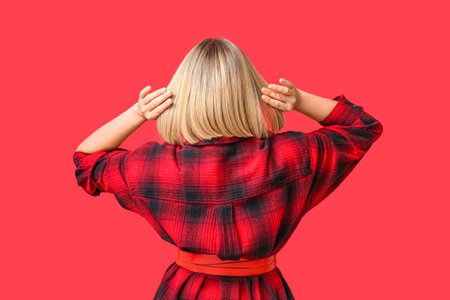 Young woman with bob hairstyle on red background, back viewの写真素材