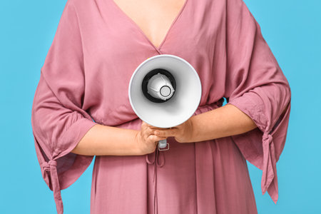 Mature woman with megaphone on blue backgroundの写真素材