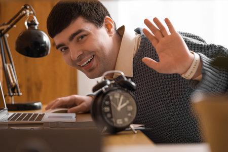 Young businessman with alarm clock at table in office, closeup