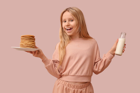 Little girl with tasty pancakes and bottle of milk on beige backgroundの写真素材