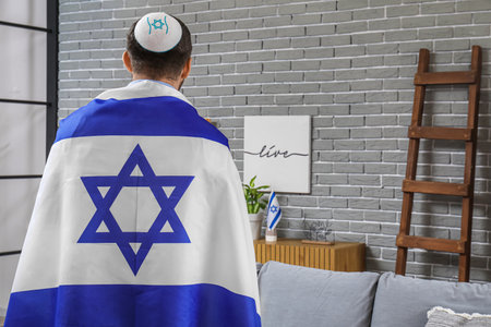 Young Jewish man in hat with flag of Israel at home, back viewの写真素材