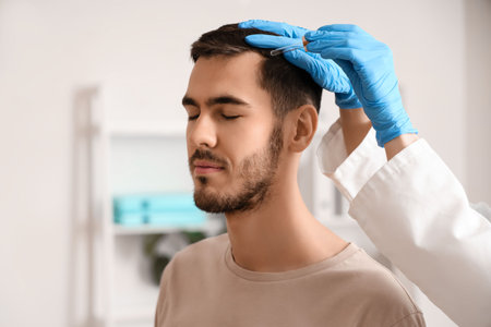 Young man receiving injection for hair growth at clinic, closeupの写真素材
