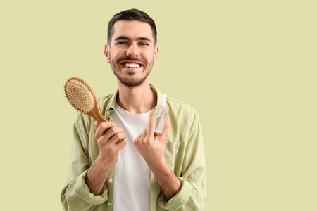 Young man with product for hair growth and brush on green backgroundの写真素材