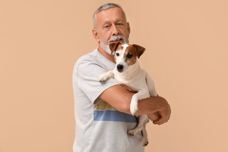 Senior man with cute dog on beige backgroundの写真素材