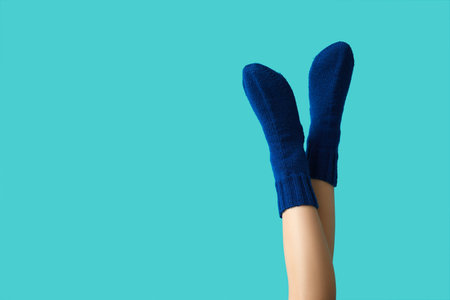 Legs of young woman in warm knitted socks on blue backgroundの写真素材