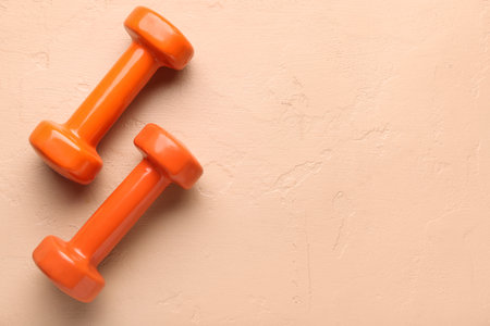 Orange dumbbells on beige backgroundの写真素材