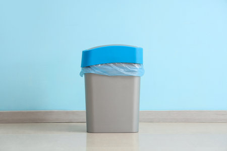 Trash bin with garbage bag near blue wallの写真素材