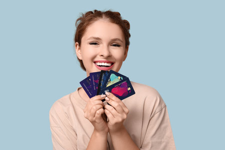 Beautiful young woman with credit cards on blue backgroundの写真素材