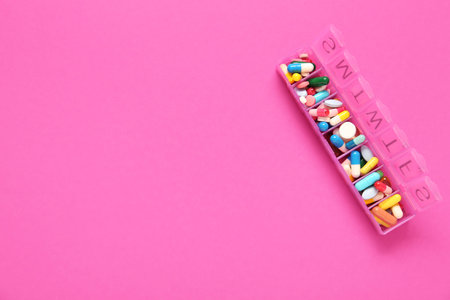 Container with different pills on pink backgroundの写真素材