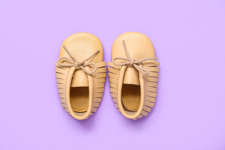 Pair of stylish baby boots on lilac backgroundの写真素材