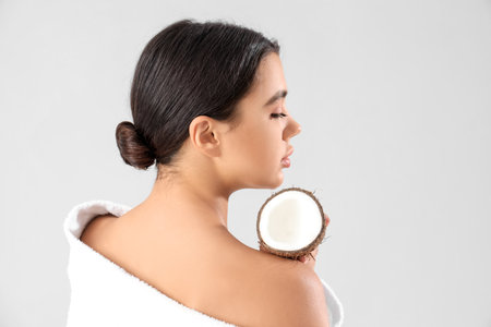 Beautiful young woman with coconut on gray background. Skin care conceptの写真素材