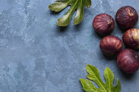 Fresh ripe figs and leaves on blue background
