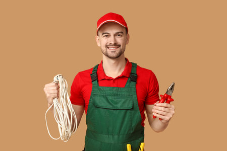 Portrait of male electrician with pliers and wires on beige backgroundの写真素材