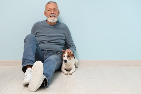 Senior man with cute dog near light blue wallの写真素材