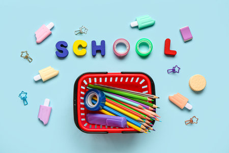 Text SCHOOL and shopping basket with different school stationery on blue backgroundの写真素材
