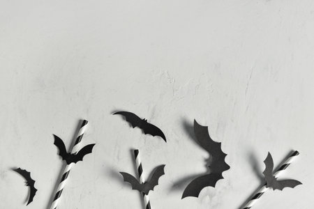 Drinking straws and paper bats for Halloween celebration on light backgroundの写真素材