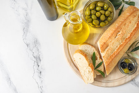 Wooden board with bread, olives and butter on white marble backgroundの写真素材