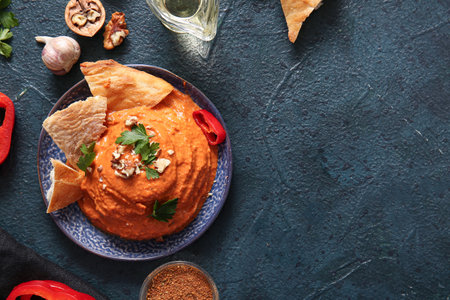 Plate of tasty muhammara and ingredients on black backgroundの写真素材