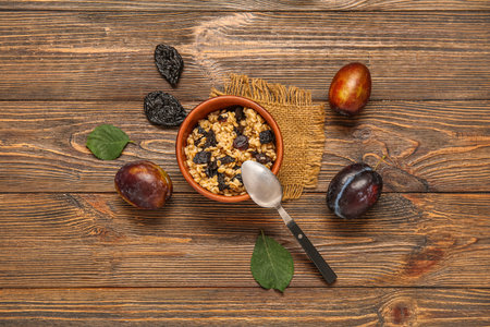 Bowl with boiled oatmeal and dried plums on wooden backgroundの写真素材