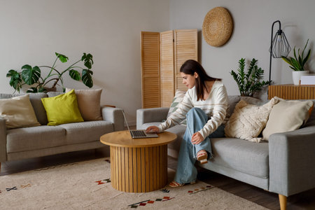 Young woman using laptop on sofa in living room