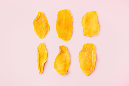 Slices of dried mango on pink backgroundの写真素材