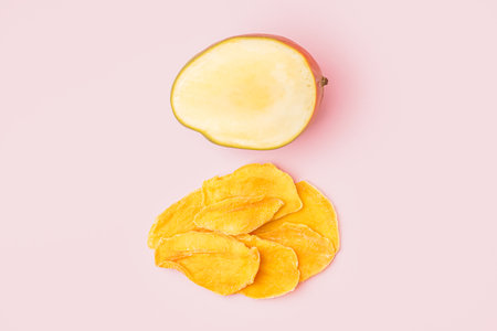 Slices of dried mango and fresh fruit on pink tableの写真素材
