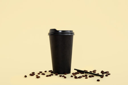 Black takeaway paper cup and beans on beige background