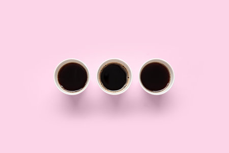 Takeaway paper cups of tasty coffee on pink backgroundの写真素材
