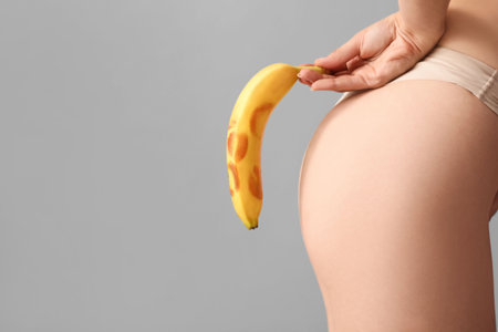 Woman holding banana with lipstick kiss marks on light background, closeup. Sex conceptの写真素材