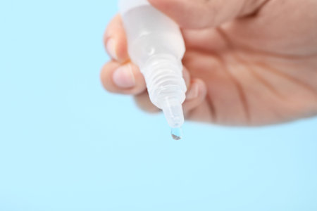 Woman with nasal drops on blue background, closeup