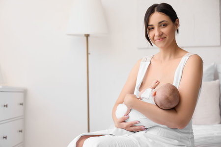 Happy mother breastfeeding her little cute baby in bedroom