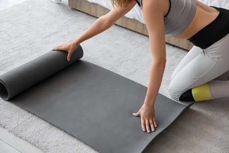 Young sporty woman with yoga mat at homeの写真素材