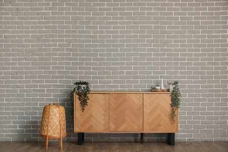 TV stand with plants and lamp near gray brick wall in room