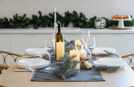 Beautiful table setting with Christmas decorations and burning candles in festive kitchen