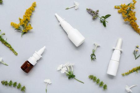 Bottles of nasal drops with different flowers on gray backgroundの写真素材