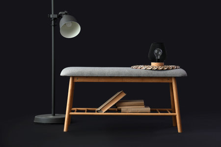 Gray bench with books and standard lamp on black backgroundの写真素材