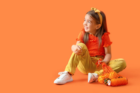 Cute little girl with string bag on orange background
